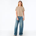 The Beauty Closet model wearing a plain beige cotton crewneck t-shirt with wide-leg blue denim jeans