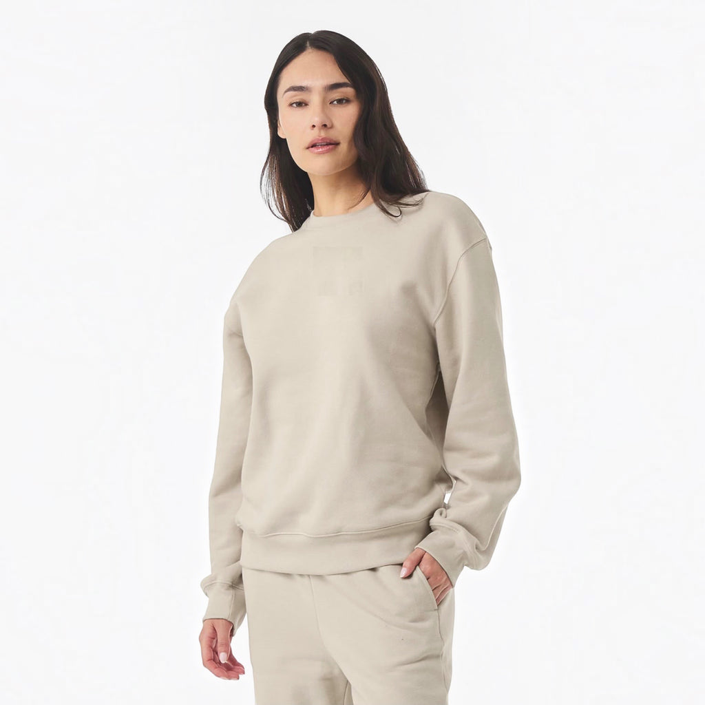 The Beauty Closet unisex beige fleece crewneck sweatshirt worn by a woman against a plain white background.