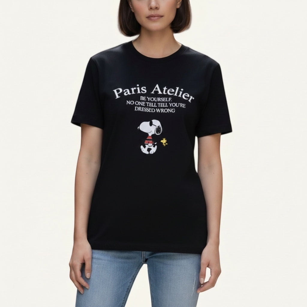 The Beauty Closet black cotton t-shirt featuring a Paris Atelier graphic print and Snoopy character illustration.