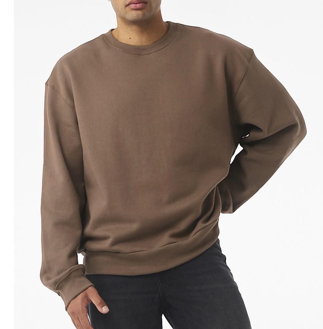 The Beauty Closet brown crewneck sweatshirt with long sleeves and ribbed cuffs. Model wears black jeans.