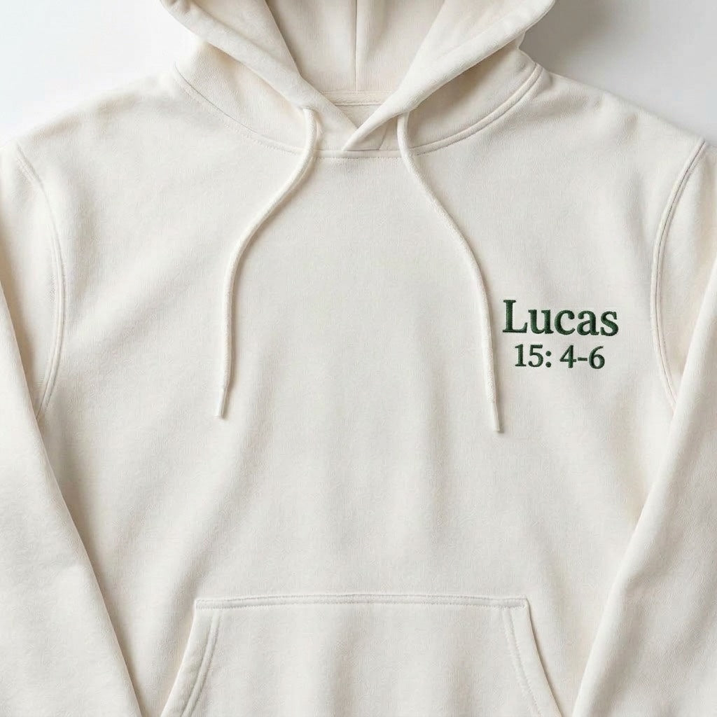 The Beauty Closet cream pullover hoodie featuring green embroidered Lucas 15:4-6 text on the chest