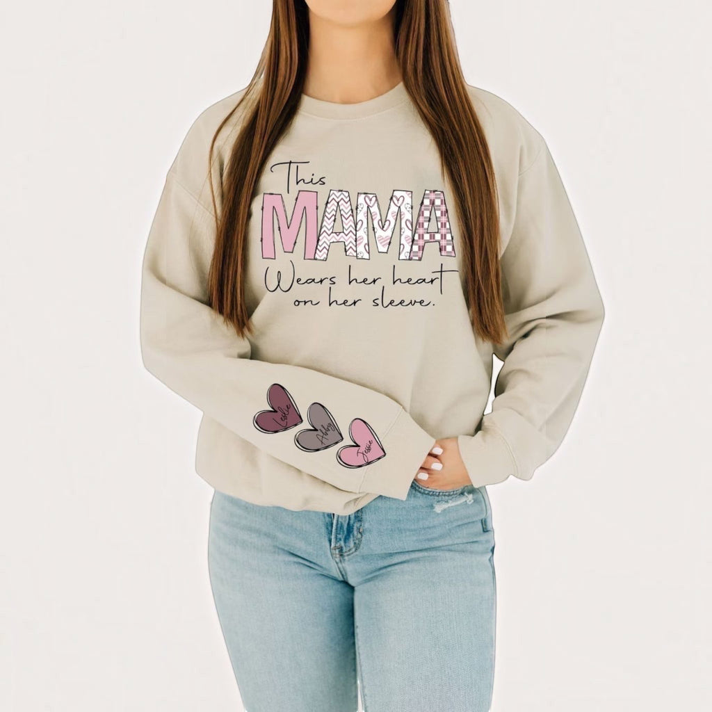 The Beauty Closet cream crewneck sweatshirt with MAMA graphic and heart sleeve detail worn by a woman