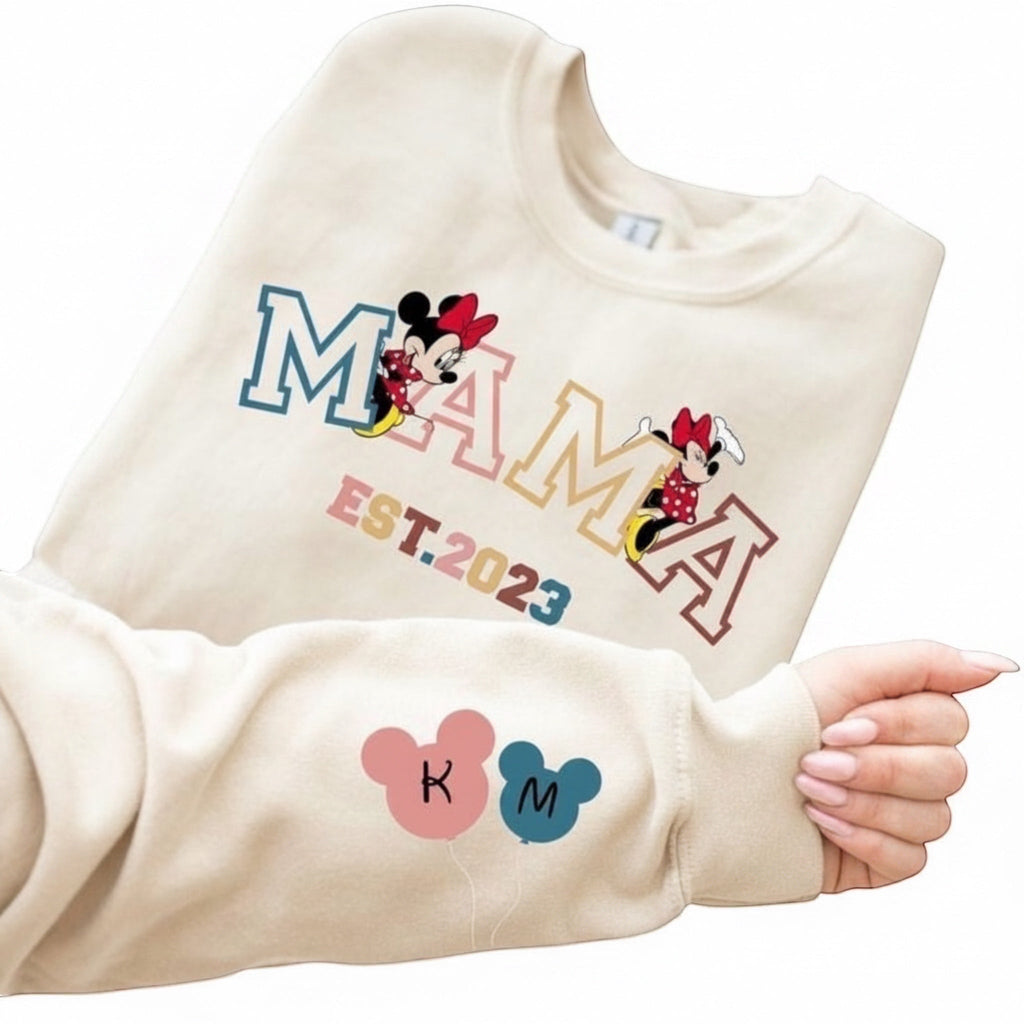 The Beauty Closet cream crewneck sweatshirt featuring a MAMA graphic with Minnie Mouse and EST. 2023 sleeve detail.