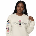 The Beauty Closet cream crewneck sweatshirt with Minnie Mouse Mama graphic and sleeve character prints on a model.