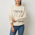 The Beauty Closet cream sweatshirt with Stronger than the storm text and a cross graphic on the sleeve