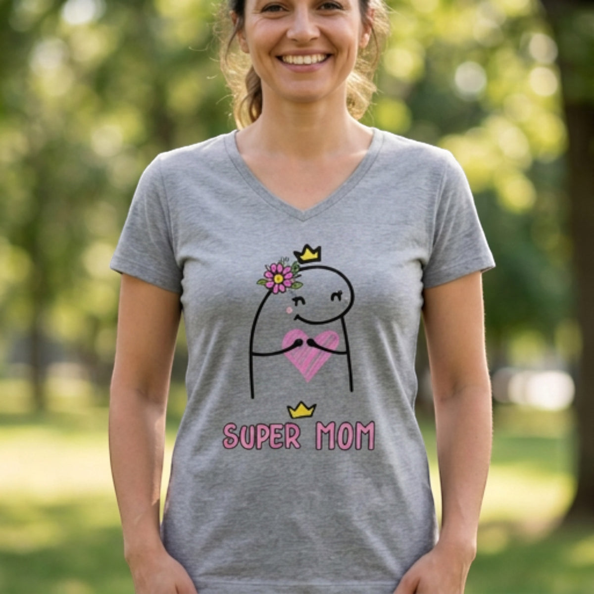 A woman wearing a grey V-neck t-shirt from The Beauty Closet featuring a Super Mom graphic with a heart and crown.