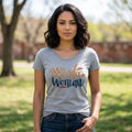 A woman wearing a grey The Beauty Closet crewneck t-shirt with Wonder Woman graphic print in blue and gold text