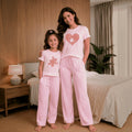 The Beauty Closet matching light pink pajama sets for mother and daughter with heart and puzzle piece graphic prints.
