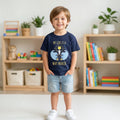 A young boy wearing a navy blue The Beauty Closet graphic t-shirt with My God Is A Way Maker text and sun design.