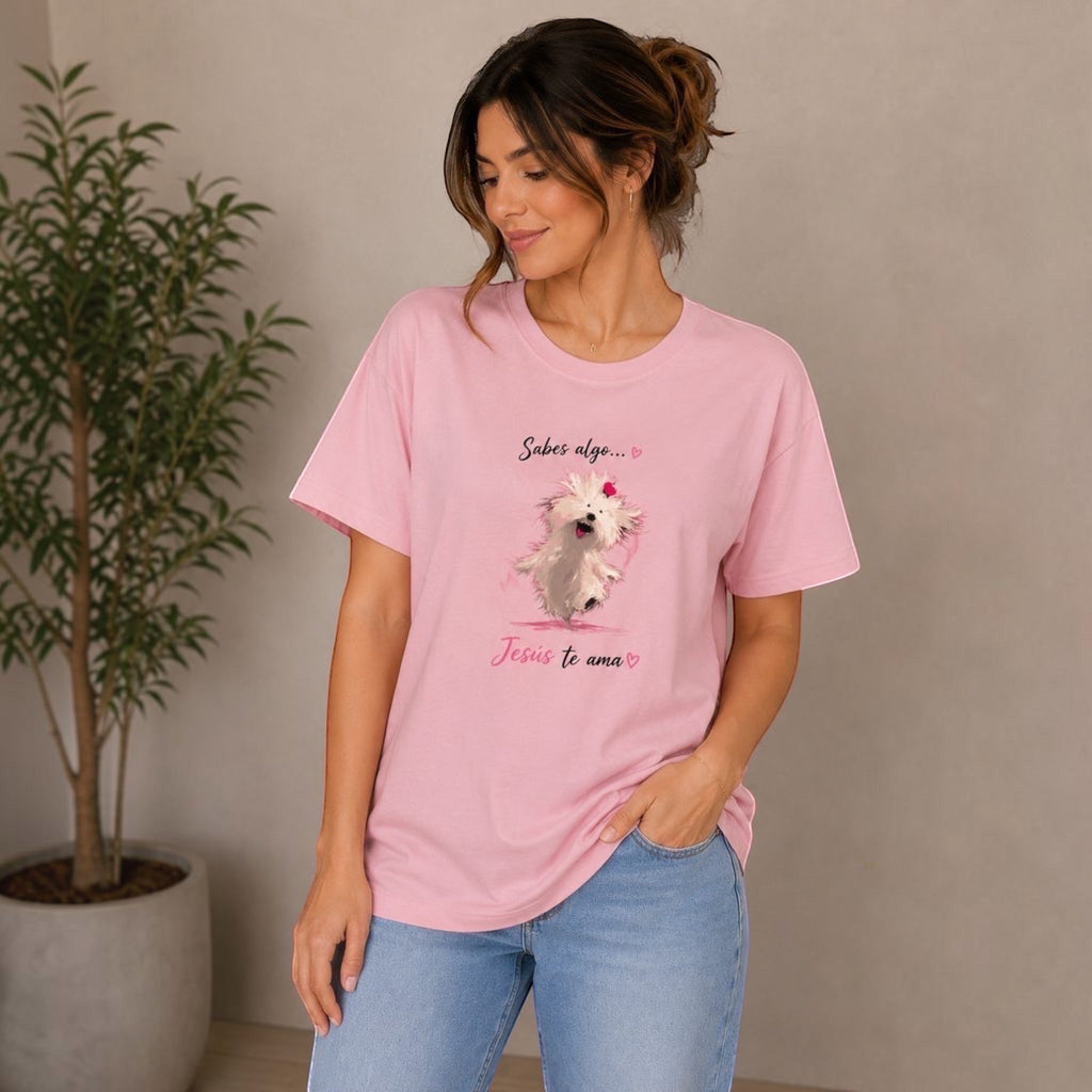 The Beauty Closet pink cotton t-shirt with a graphic of a fluffy white dog wearing a red bow, with Spanish text "Sabes algo... Jesus te ama"