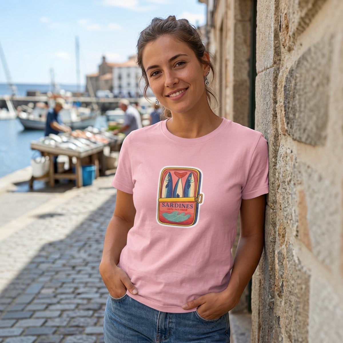 The Beauty Closet pink cotton crewneck t-shirt featuring a sardine tin graphic print worn by a woman outdoors.