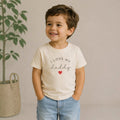 Toddler wearing a cream The Beauty Closet t-shirt with I Love My Daddy text and a small red heart graphic.