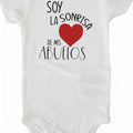 The Beauty Closet white cotton baby bodysuit with a red heart graphic and Spanish text print.