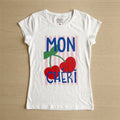 The Beauty Closet white cotton crewneck t-shirt featuring a Mon Cheri cherry graphic print on pink vertical stripes.