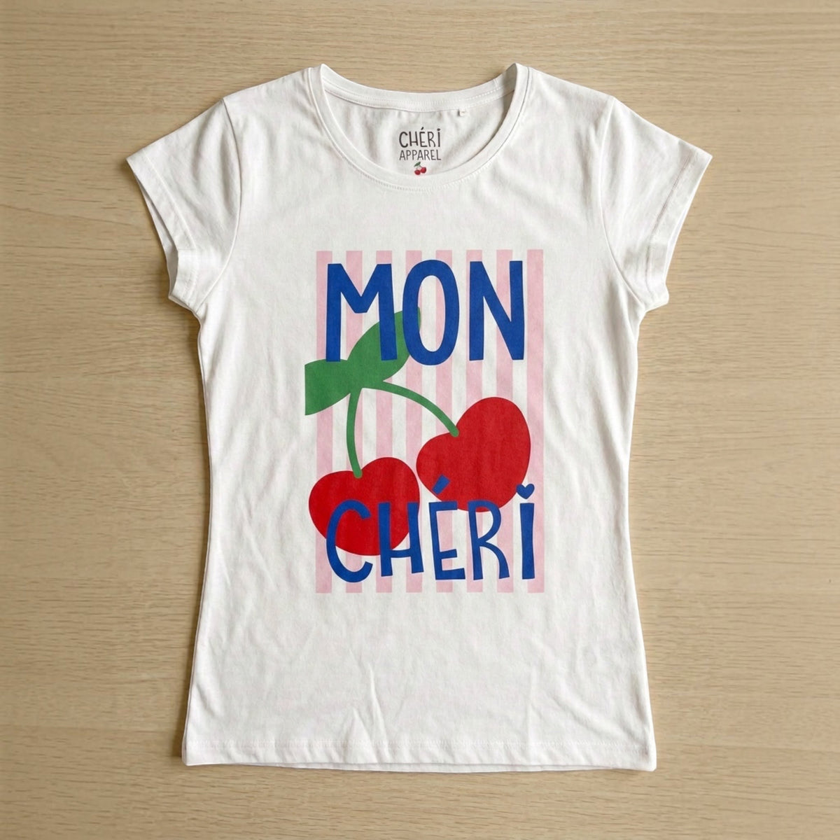 The Beauty Closet white cotton crewneck t-shirt featuring a Mon Cheri cherry graphic print on pink vertical stripes.