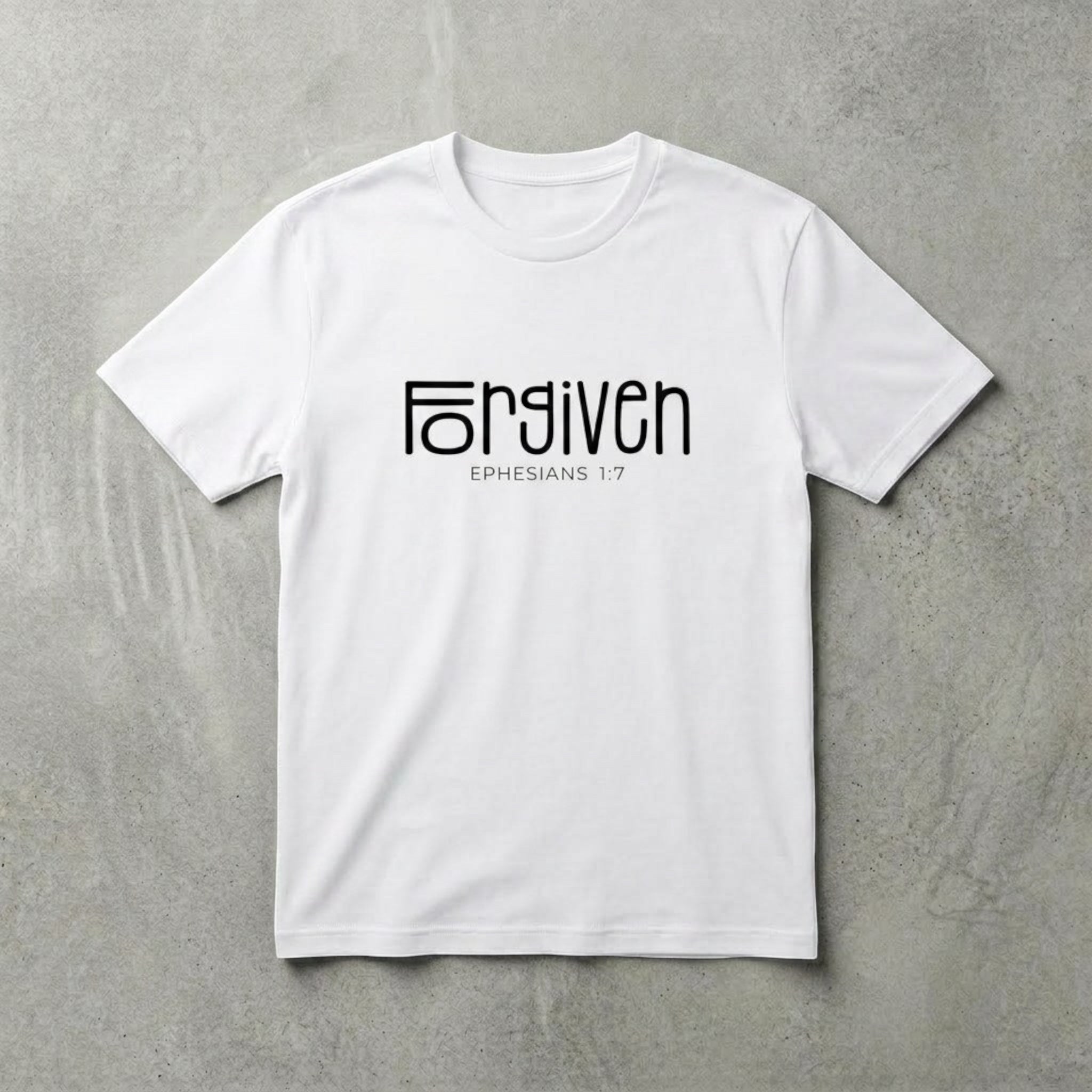 The Beauty Closet white cotton t-shirt with black Forgiven Ephesians 1:7 graphic print on a grey textured background.