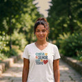 The Beauty Closet white v-neck t-shirt with colorful Confia en el Senor graphic worn by a woman in a park