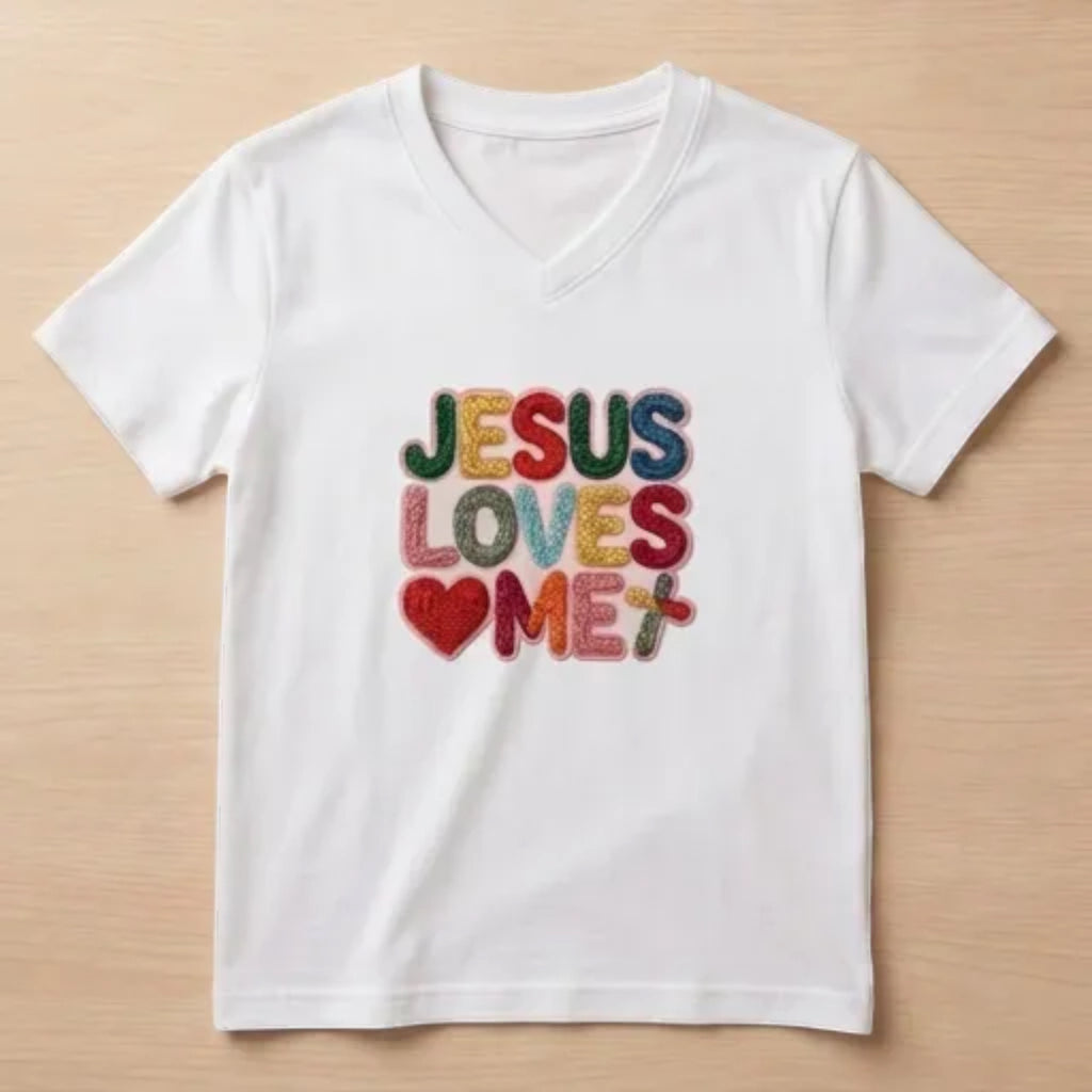 The Beauty Closet white v-neck t-shirt featuring colorful embroidered Jesus Loves Me text and a heart patch.